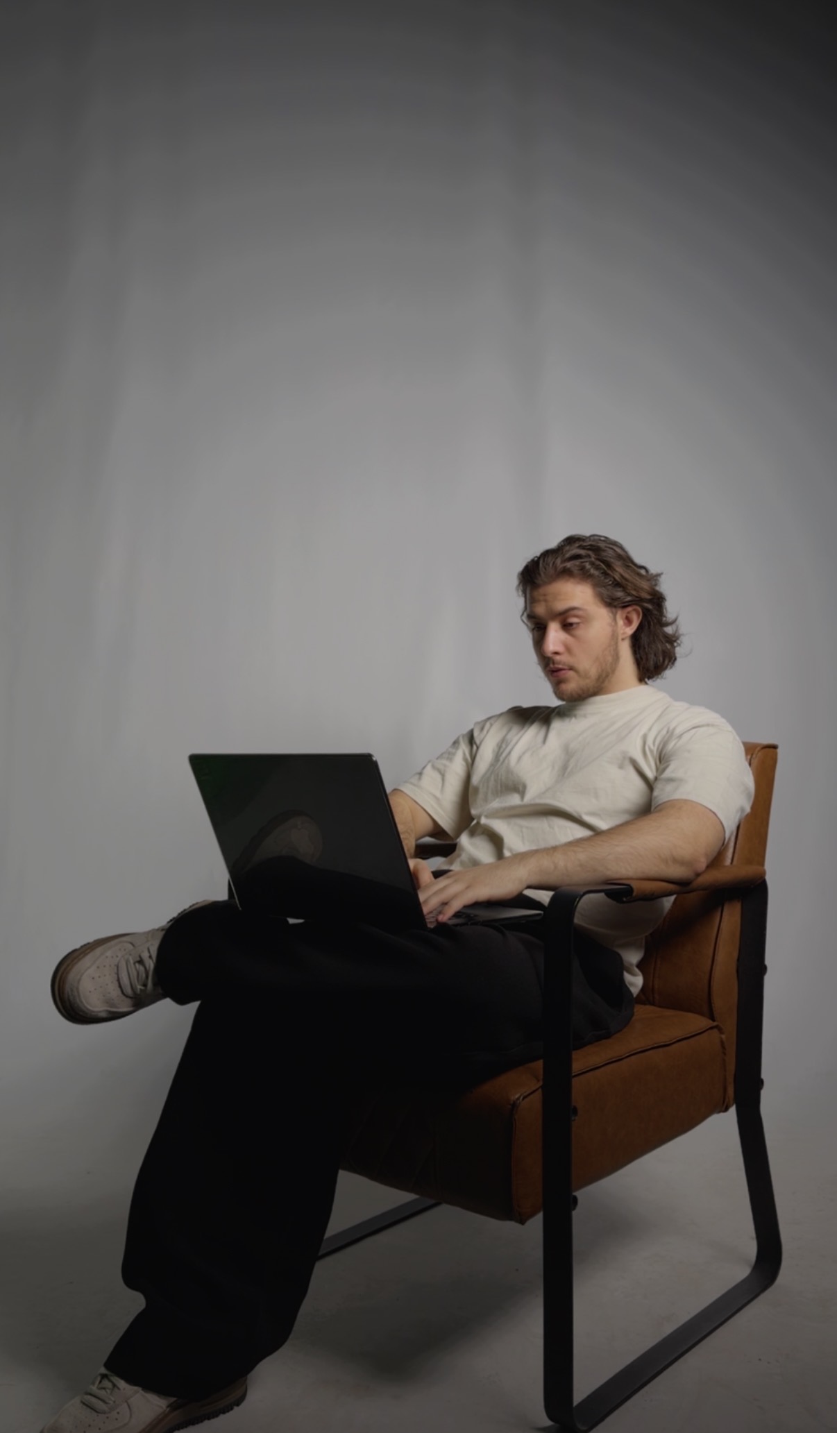 Davide Di Turi aan het werk op een laptop, zittend in een lederen stoel.